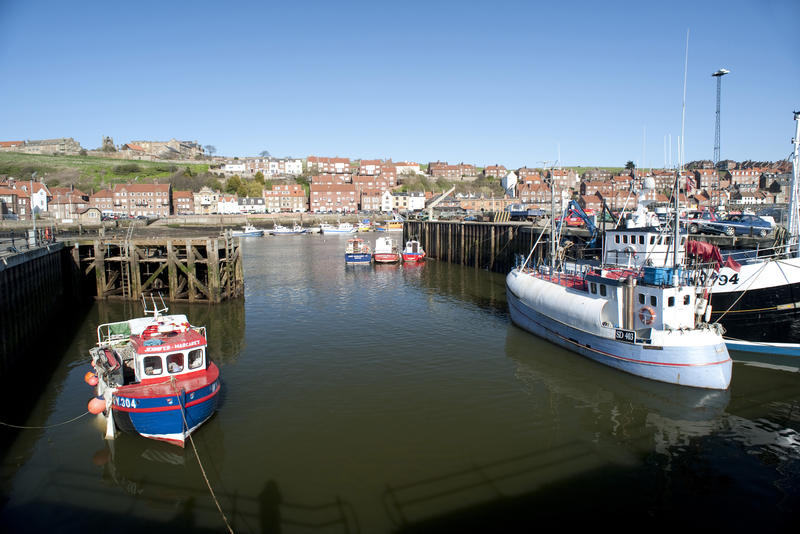 Upper harbour in Whitby with fishing boats and a trawler moored in the calm water