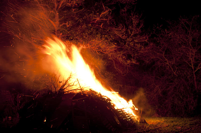 Flaming bonfire shooting bright orange flames into the night sky as the fire takes a hold on the wood and fuel