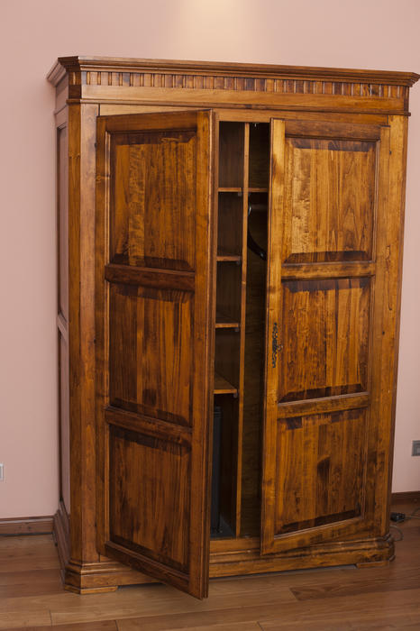 Rustic old wooden wardrobe or cabinet standing with the doors ajar showing the empty storage shelves inside