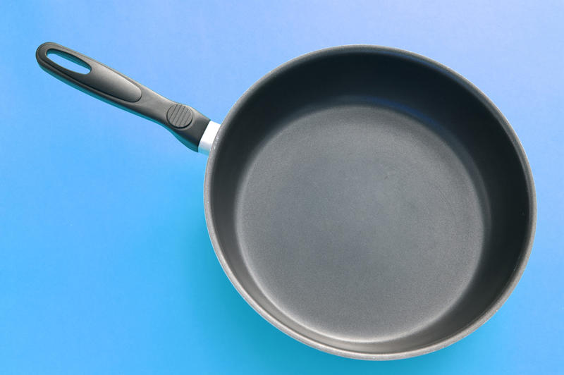 Close up One Clean Black Frying Pan on a Sky Blue Gradient Background