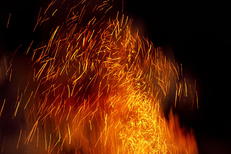 Glowing embers leaving fiery trails through the darkness as they are sucked up by the draught above a blazing bonfire creating a beautiful fiery abstract background pattern