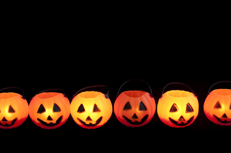 Line of Halloween pumpkin jack-o-lanterns glowing in the dark with plenty of copyspace above for your greeting or invitation