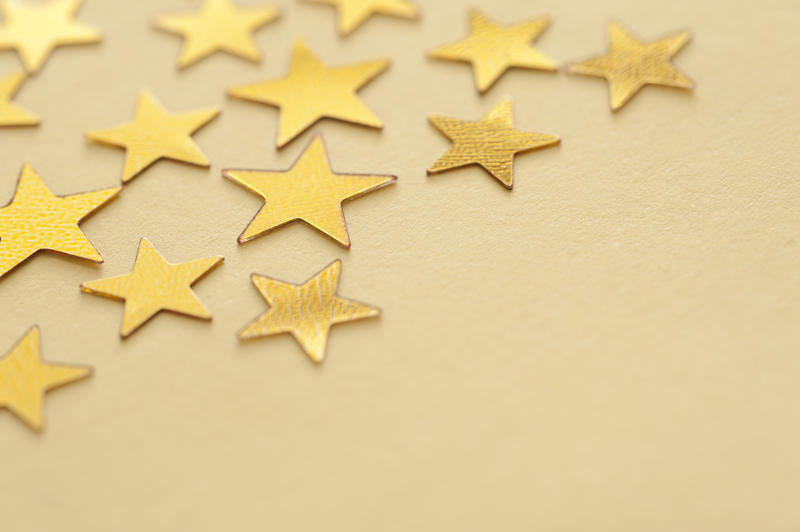 Gold star background with copyspace for your festive or Christmas greeting viewed at an oblique angle scattered on a yellow background