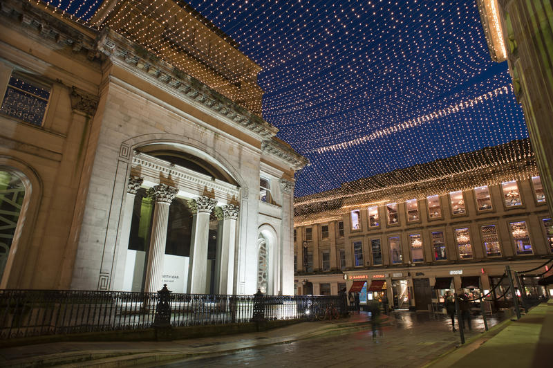 Royal Exchange Square and the GOMA building, or Gallery Of Modern Art, in Glasgow illuminated at night with festive Christmas lights strung overhead