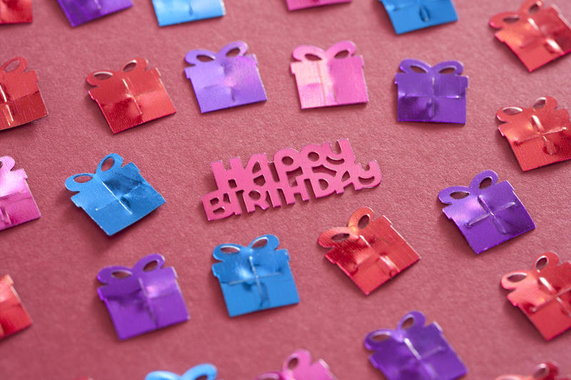 Happy Birthday festive background with small gift decorations and pink text for a girl on a matching pink background