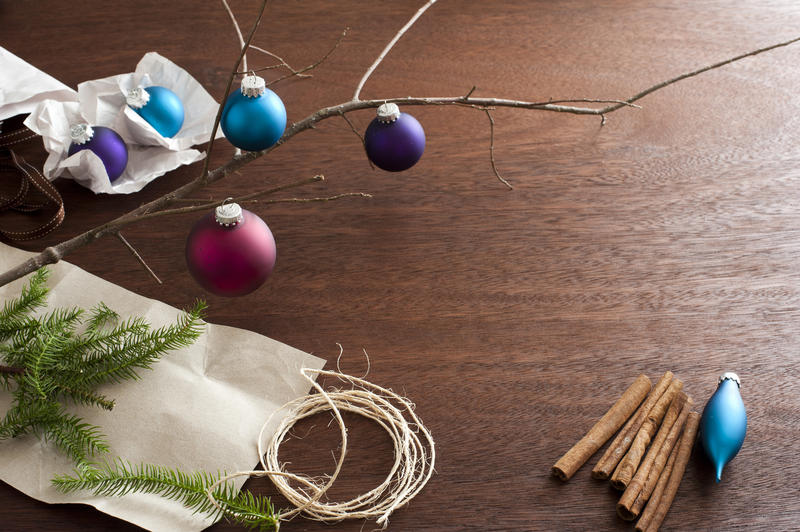High Angle View of Bare Tree Branch on Textured Wooden Surface Scattered with Christmas Ornaments, Evergreen Sprigs, String and Cinnamon Sticks - Festive Still Life with Copy Space