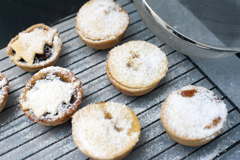 High angle view of a batch of fresh home baked traditional fruity Christmas mince pies sprinkled with icing sugar and decorated with Christmas trees