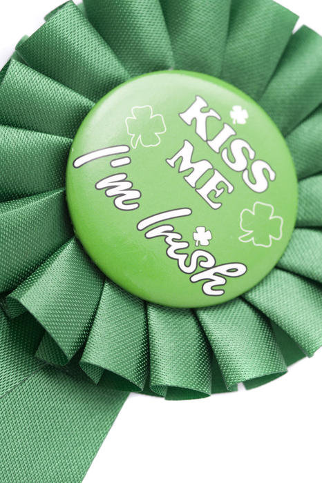 A novelty green ribbon rosette with a st patricks day message in the middle