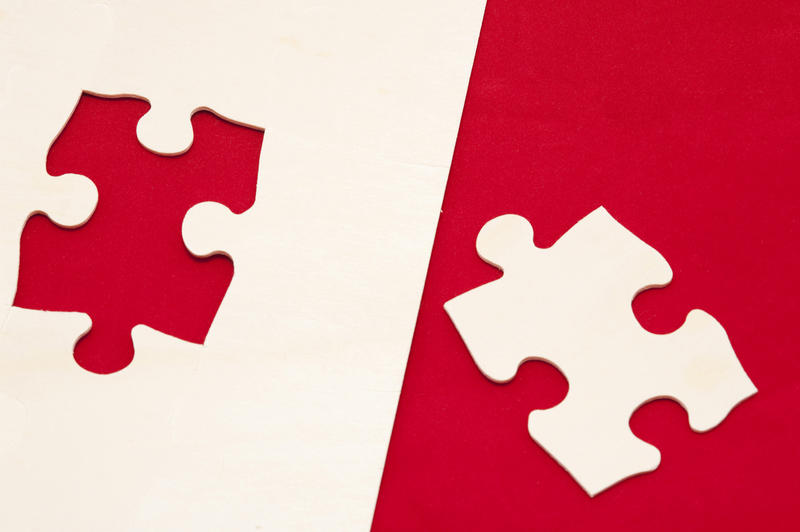Matching puzzle pieces in red and white on a divided bicolor background in a problem solving and solution concept