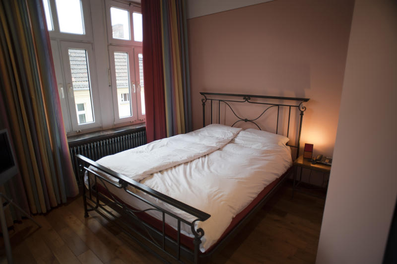 Large bedroom with a classic wrought iron bed and large window overlooking an urban building