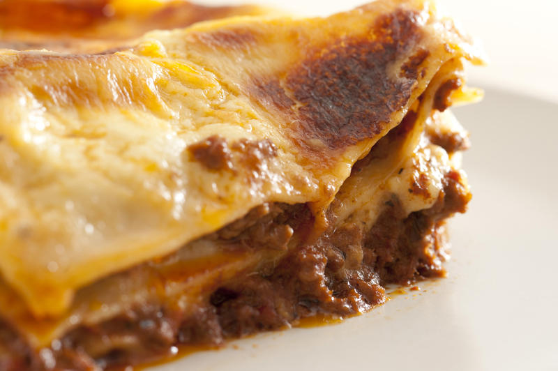 Close up Edge of Freshly Cooked Tasty Italian Lasagne Dish on a White Plate.