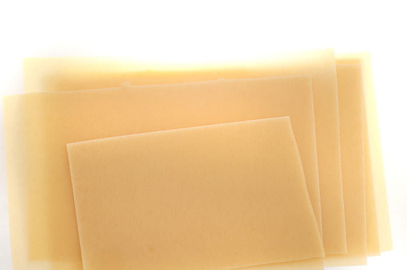 Dried uncooked traditional Italian lasagne sheets made from durum wheat dough on a white background