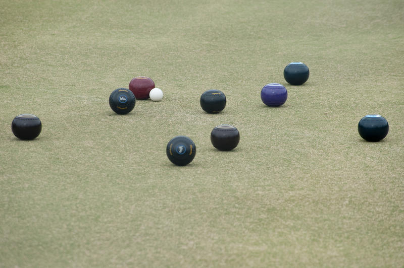 Bowling balls lying around a jack on a bowling green in a game of lawn bowls with copyspace below