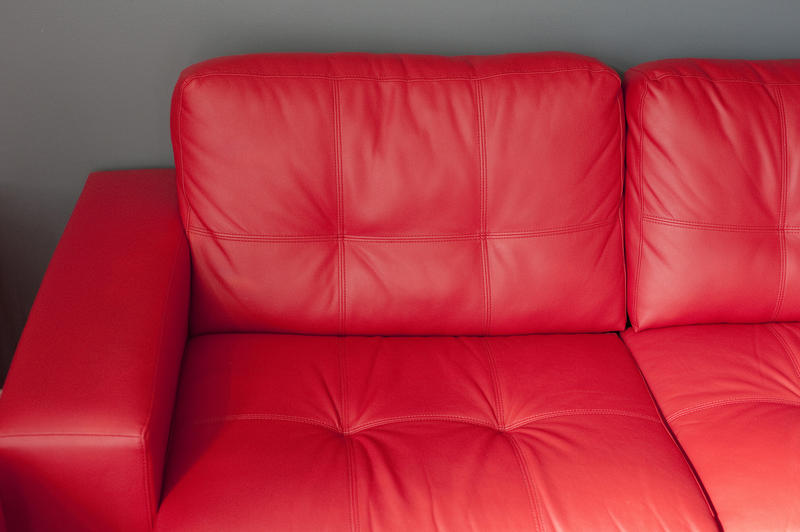 Close up Elegant Glossy Red Leather Sofa in Front a Gray Wall at the Living Room