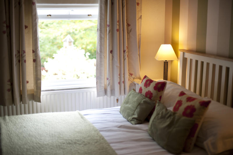 Bedroom with a lovely light garden view through an open window looking across a comfortable double bed