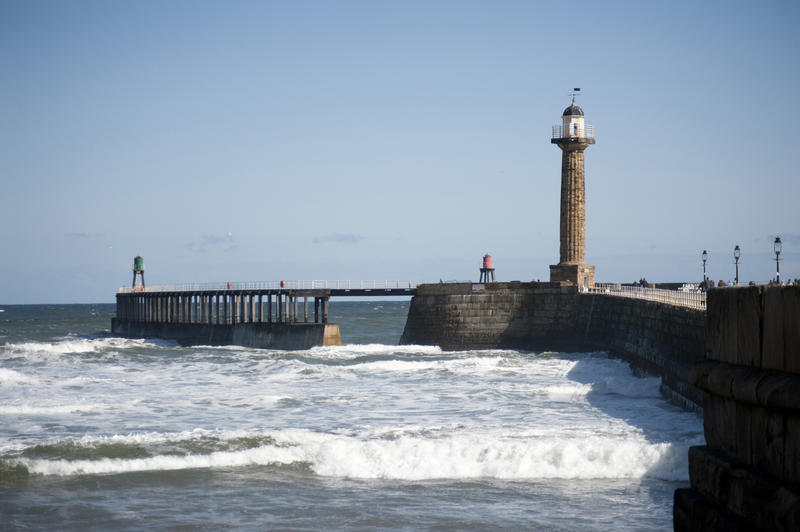 West navigation lighthouse at Whitby on the stone pier and extended breakwater protecting the entrance to the harbour from the ocean currents and surf
