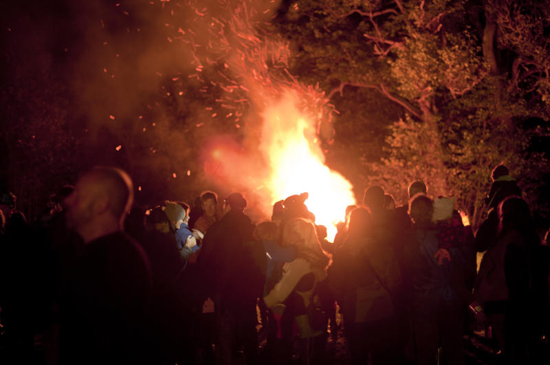 November 5th celebrations with a large crowd of people gathered around a bonfire in a field with trees commemorating Guy Fawkes or Bonfire Night - not model released