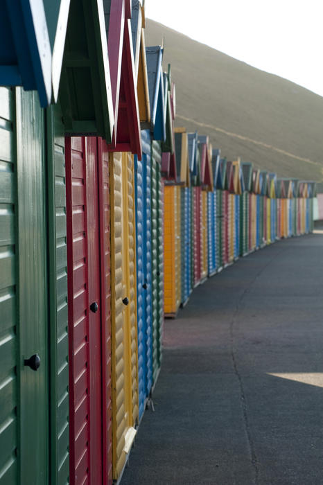Receding row of colourful wooden beach huts for changing and dressing at Whitby West Cliff