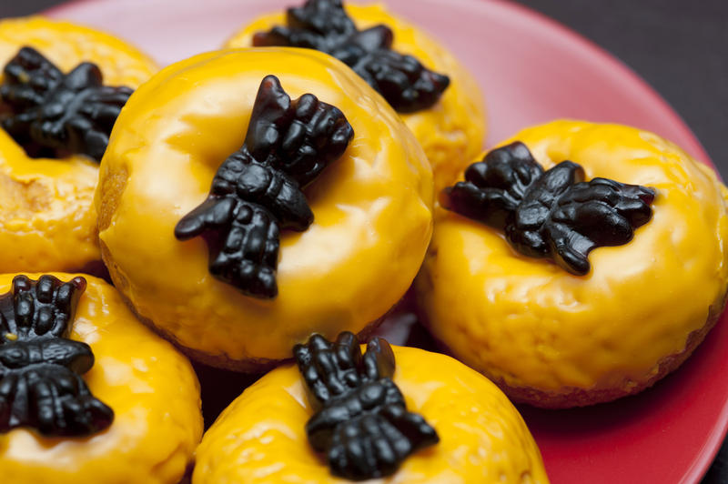 Halloween doughnuts frosted in orange icing and decorated with spooky jelly spiders for trick-or-treating