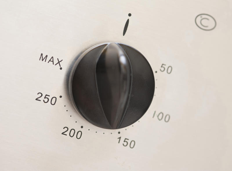 Thermostat control on an oven with a central plastic knob surrounded by temperature settings for cooking food