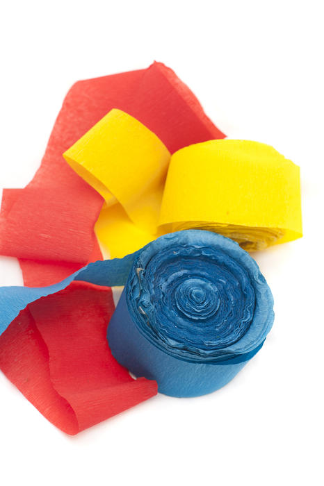 Close up Rolled Paper Celebration Streamers in Blue, Red and Yellow Colors Against White Background.