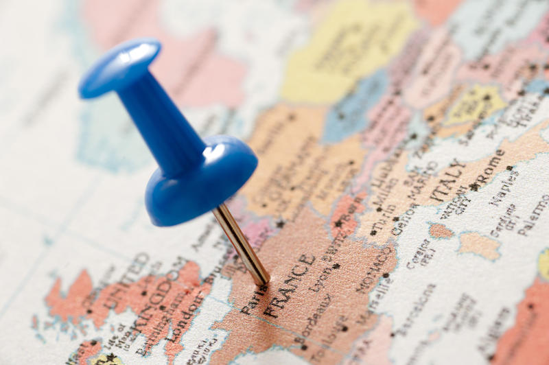 Close Up of Blue Thumb Tack Location Marker Inserted in Paris on Map of France and Europe