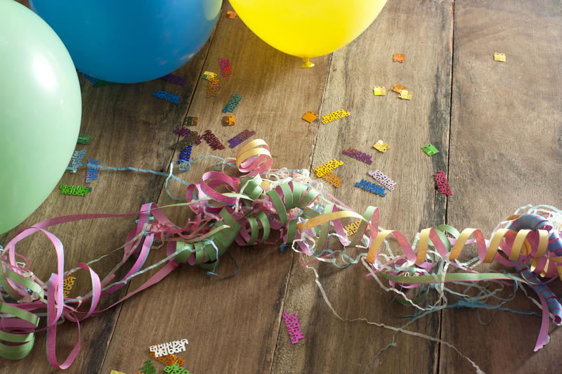 Close up Birthday Party Balloons, Confetti and Streamers on a Wooden Table.