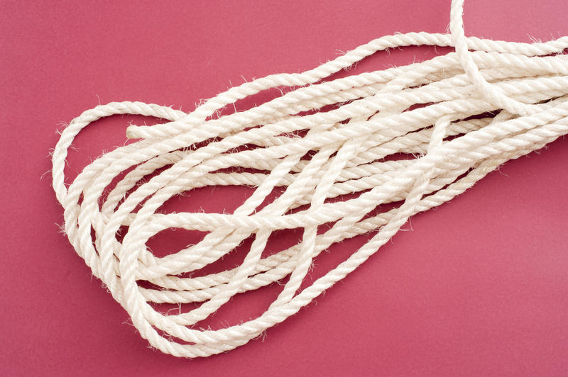 Piece of coiled clean white rope on a red background showing texture of the fiber