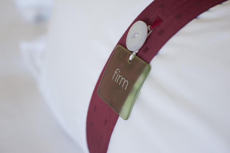 Tag on a hotel pillow denoting the firmness of the support provided by the filling attached to a decorative purple band around the pillow