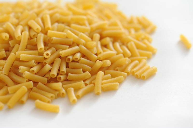 Pile of dried macaroni made from durum wheat dough on a white background for use as an ingredient in Italian cooking