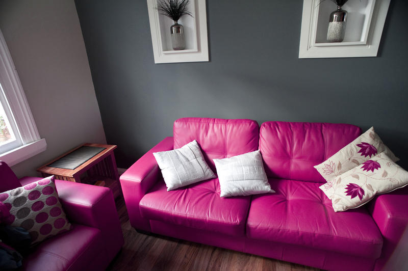 Stylish bright pink lounge suite with a comfortable sofa with decorative cushions in an interior decor concept