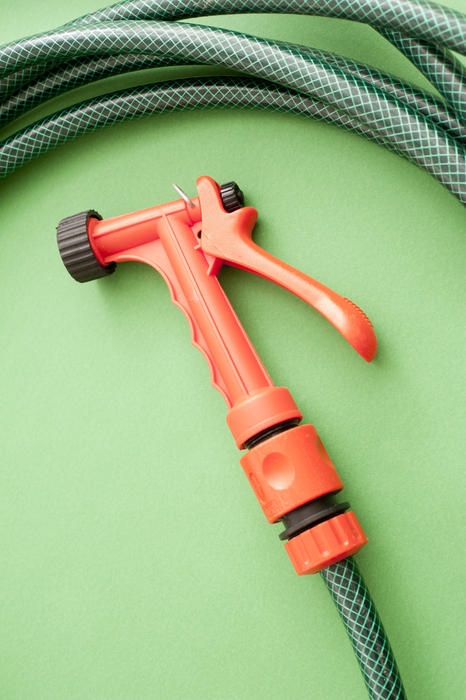 a hand held garden hose pipe water spray trigger on a green coloured background