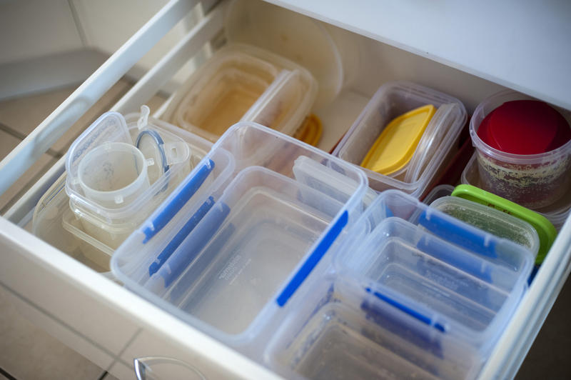 Plastic kitchen containers stacked neatly inside an open kitchen drawer for storage