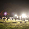 8894   People on a sports field lit by bright spotlights