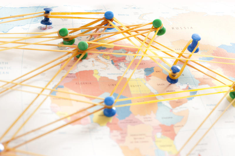 Conceptual Image of Push Pins Inserted in Various Locations on World Map Connected with Rubber Bands