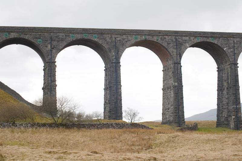 Stone arches supporting a historical Victorian railway viaduct, low angle view fom below