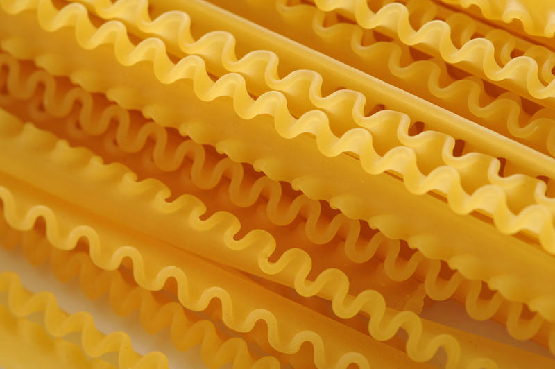 Background Close Up of Frilled Edges of Dry Lasagna Noodles - Arranged in Diagonal Pattern Across Frame