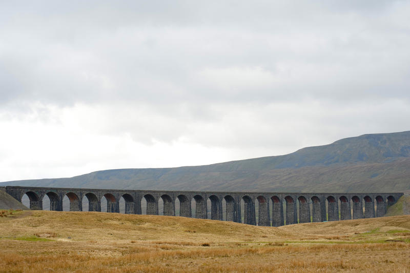 Panoramic view of the stone arches of the Ribblehead Viaduct, a curved stone Victorian railway viaduct crossing the River Ribble in North Yorkshire