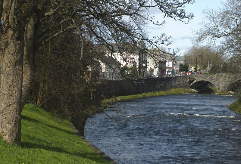 River Kent at Kendal flowing through neatly manicured banks and under an old stone bridge in Cumbria, England
