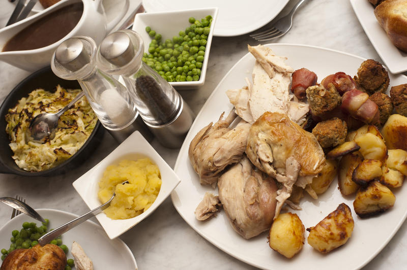 Delicious roast dinner laid out on the table with carved roast chicken or turkey with roast potatoes and accompanying vegetables in individual dishes
