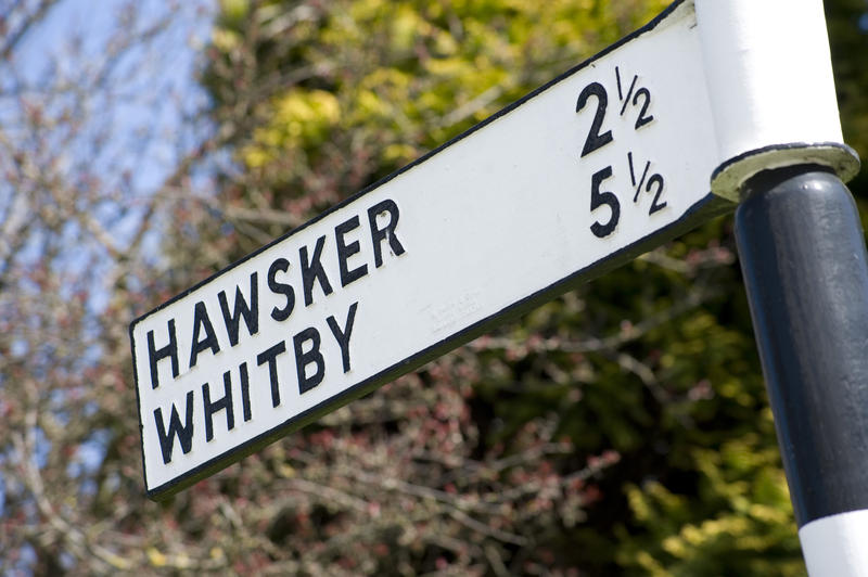 Old sign post in the fishing village of Robin Hoods Bay with distance markers for Whitby and Hawkser on the North Yorkshire coast