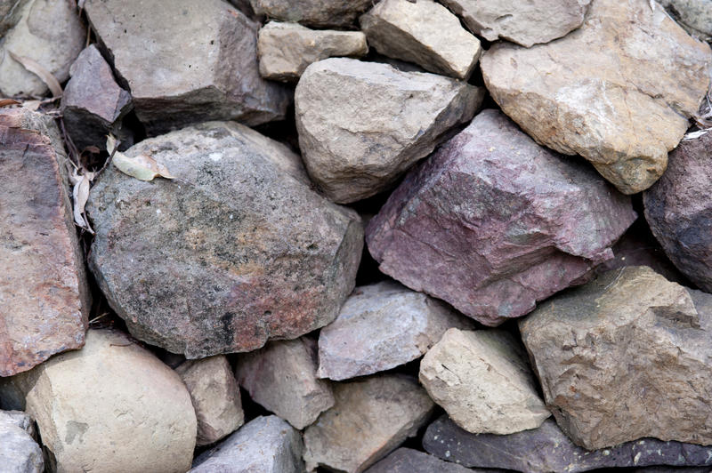Background texture and pattern of natural irregular shaped rocks in a dry stone embankment or wall