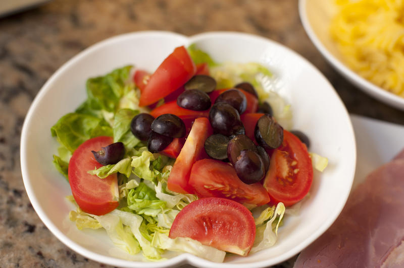 Fresh tomato and lettuce salad topped with black grapes for a tasty appetizer or accompaniment to lunch
