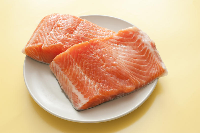 Close up Fresh Protein Rich Salmon Fish Meat Slices on a White Plate Placed on a Yellow Table.
