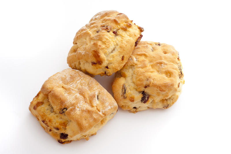 Trio of freshly baked fruity raisin scones displayed stacked over a white background with copyspace