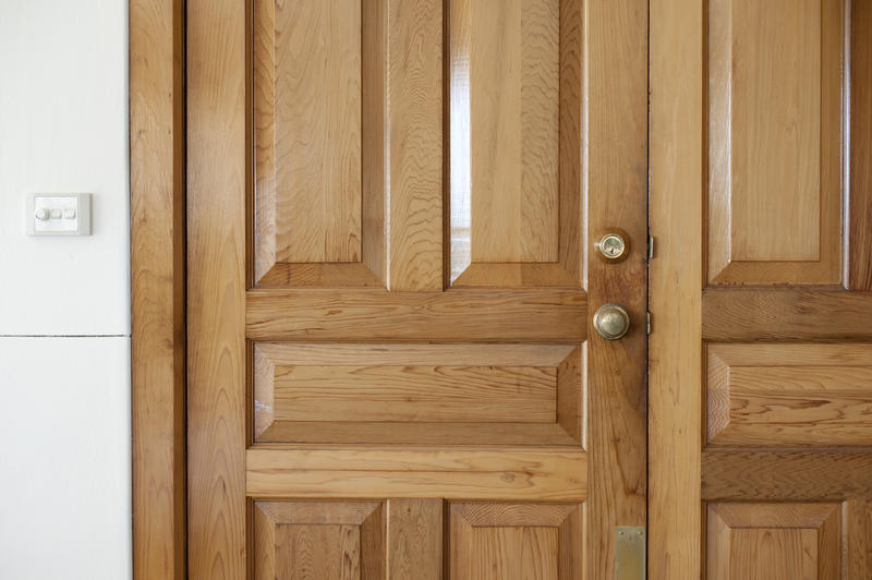 Closed natural wood paneled double front door with security locks for protection against theft and forced entry