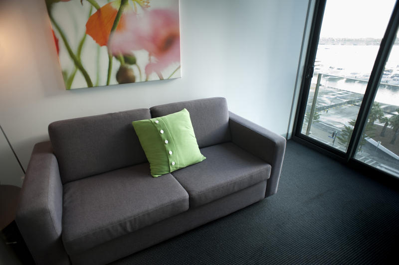 Comfortable upholstered grey sofa in a small urban apartment with a large view window