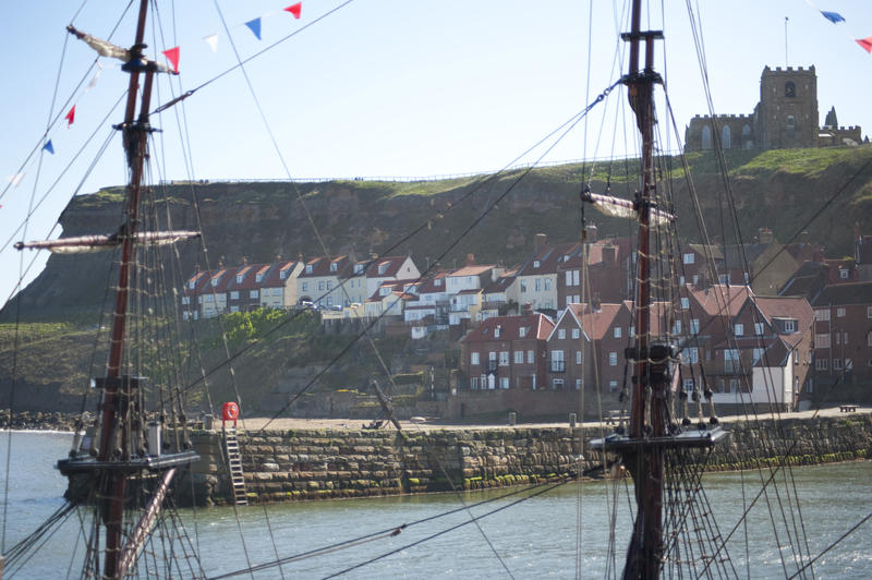 Masts and rigging of the Bark Endeavour full size replica moored at Whitby with Tate Hill and St Marys church in the background