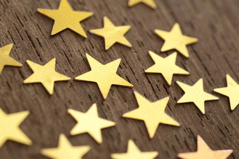 Close up shot of golden stars on wooden background