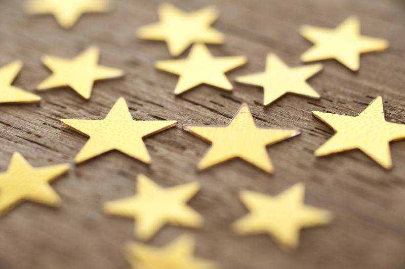 Close Up of Gold Stars Scattered on Wooden Surface, Full Frame Background with Shallow Depth of Field